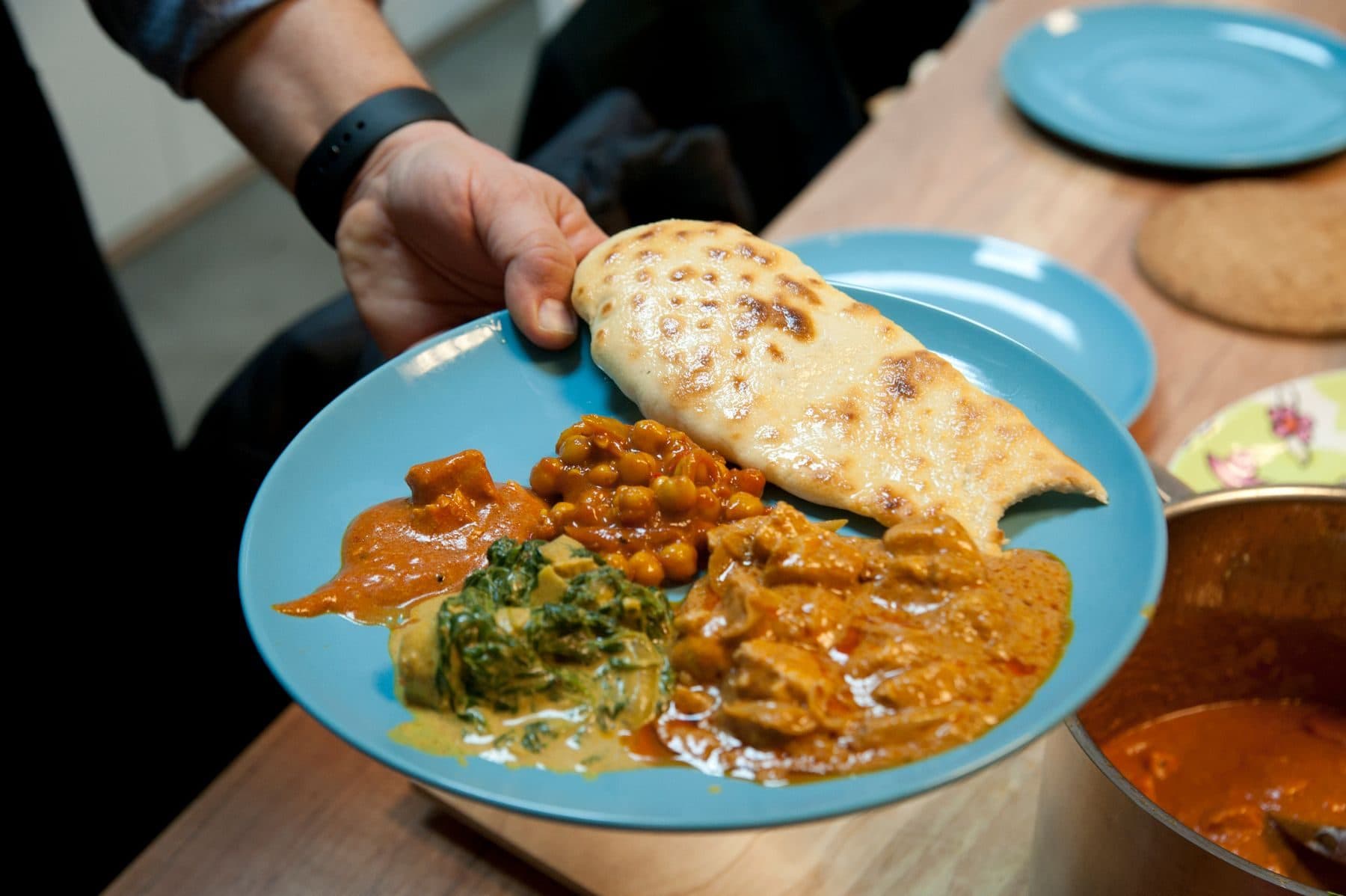 Naan, dal and paneer on a plate being served at a home dinner