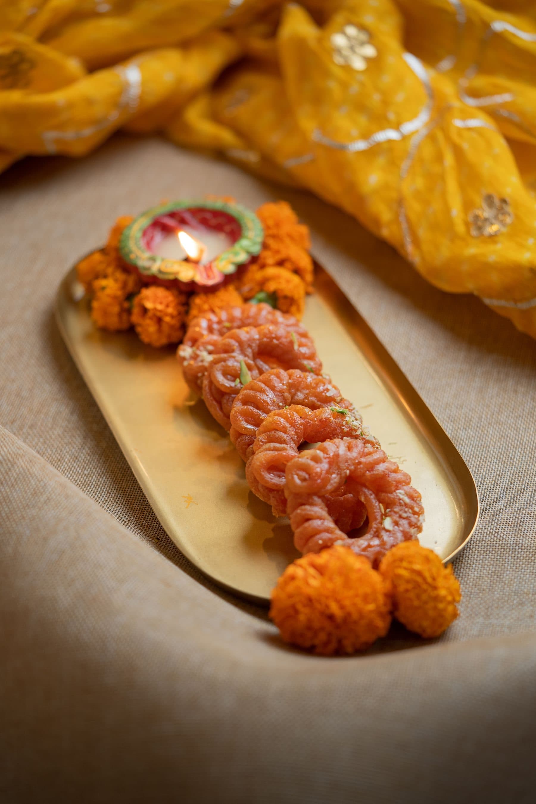 Imarti on a gold tray with marigolds and yellow silk
