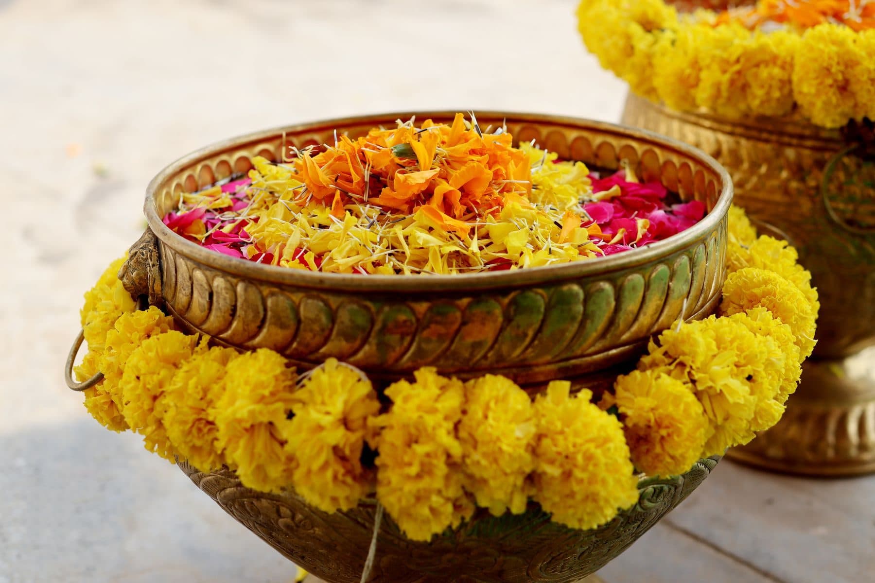 A brass urn wreathed in marigolds and filled with floating petals