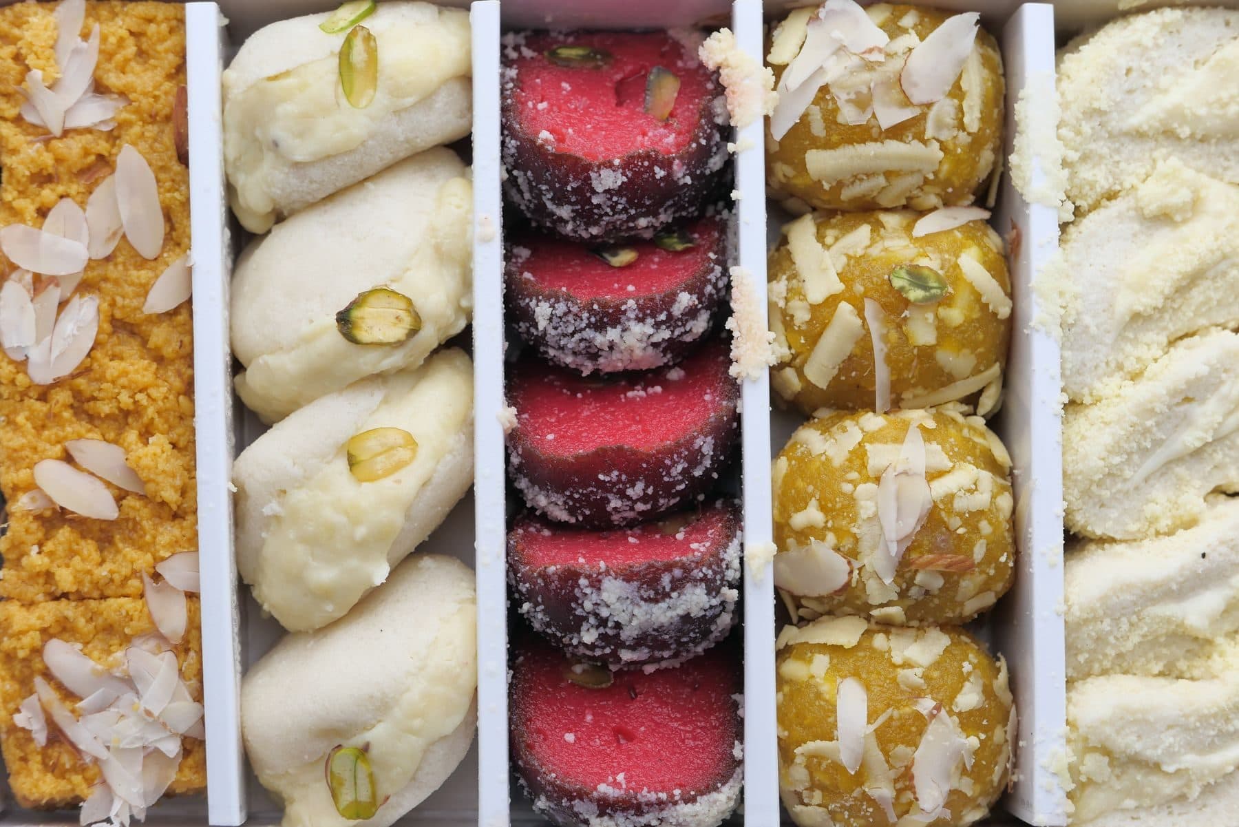 A closed assorted mithai box with pista, almond and rose varieties